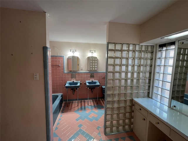 bathroom featuring tile patterned flooring, a tub to relax in, tile walls, and sink