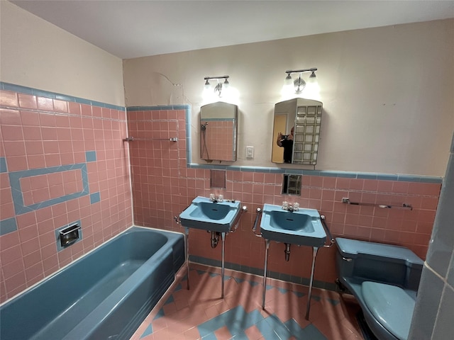 bathroom featuring toilet, tile patterned floors, tile walls, and sink