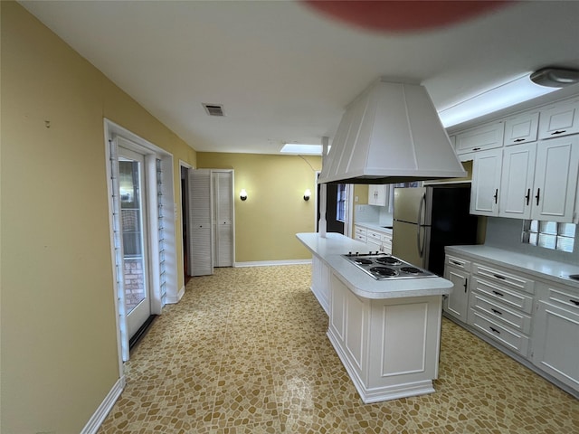 kitchen with a center island, refrigerator, stainless steel cooktop, white cabinetry, and custom range hood