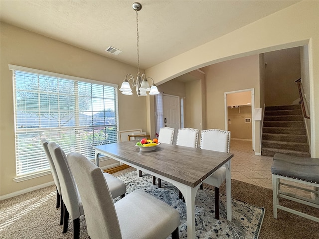 carpeted dining room featuring a wealth of natural light and a notable chandelier