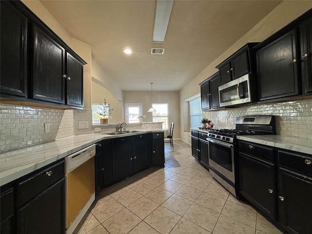 kitchen with decorative backsplash, sink, pendant lighting, and appliances with stainless steel finishes