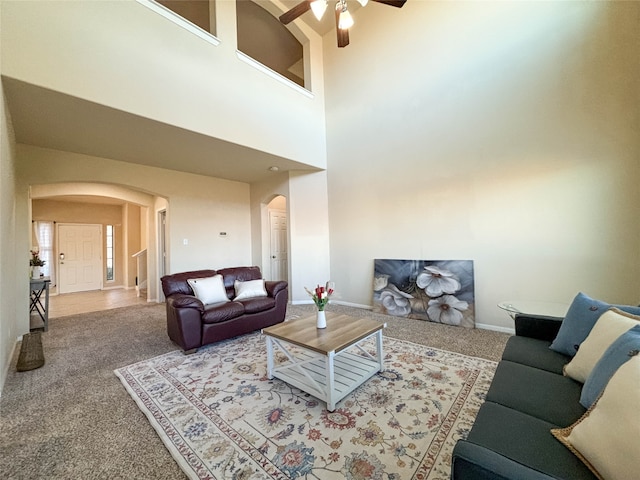 carpeted living room featuring ceiling fan and a towering ceiling