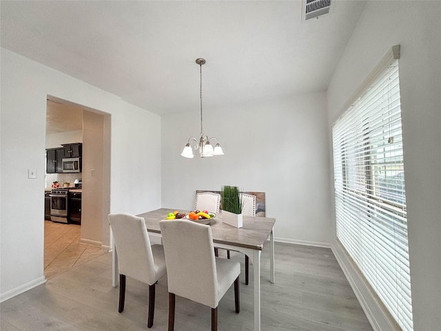 dining space with a notable chandelier and light hardwood / wood-style floors