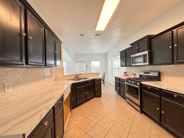 kitchen with pendant lighting, sink, light tile patterned floors, backsplash, and stainless steel appliances