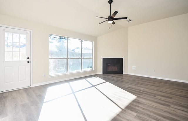 unfurnished living room featuring hardwood / wood-style flooring, vaulted ceiling, a wealth of natural light, and a tiled fireplace