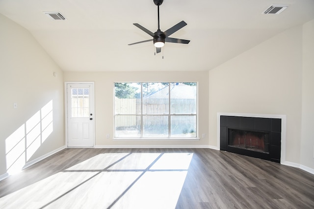 unfurnished living room featuring plenty of natural light, wood-type flooring, and a tiled fireplace