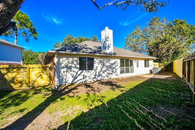 rear view of property with central AC and a yard