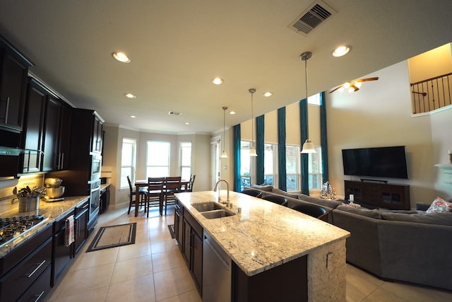 kitchen featuring sink, stainless steel appliances, an island with sink, pendant lighting, and ornamental molding