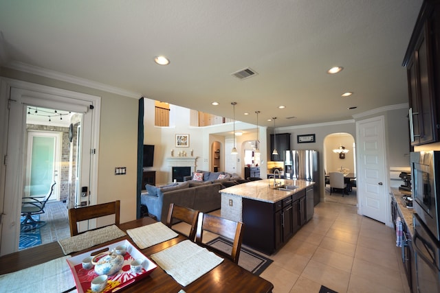 tiled dining room with ornamental molding, sink, and a chandelier