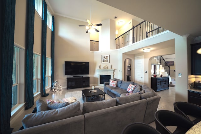 tiled living room with ceiling fan, a high ceiling, and ornamental molding