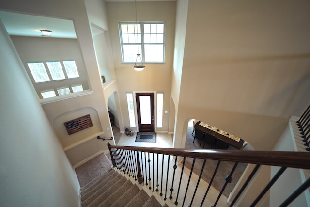 stairway with carpet and a high ceiling