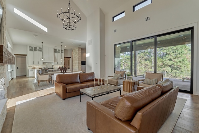 living room with light hardwood / wood-style flooring, high vaulted ceiling, and a chandelier