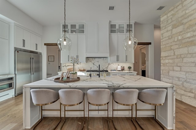 kitchen featuring light hardwood / wood-style flooring, stainless steel appliances, and an island with sink