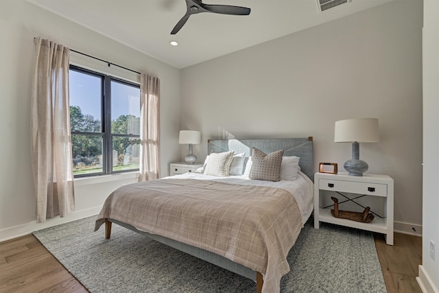 bedroom with wood-type flooring, multiple windows, and ceiling fan