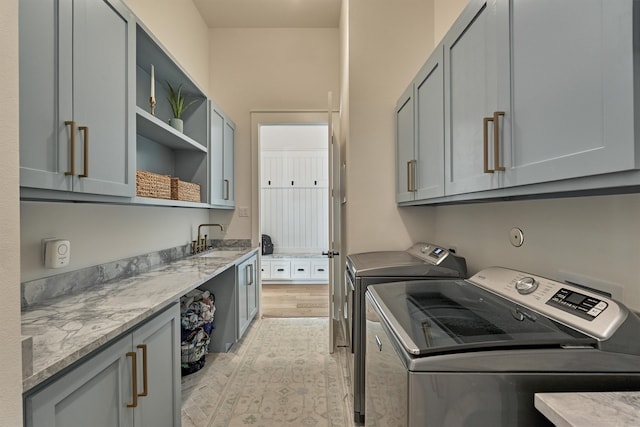 washroom featuring cabinets, separate washer and dryer, light hardwood / wood-style floors, and sink