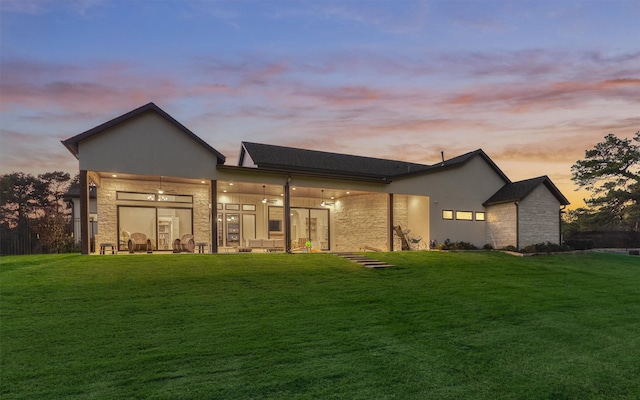 back house at dusk featuring a yard