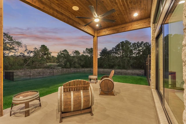 patio terrace at dusk with ceiling fan and a yard