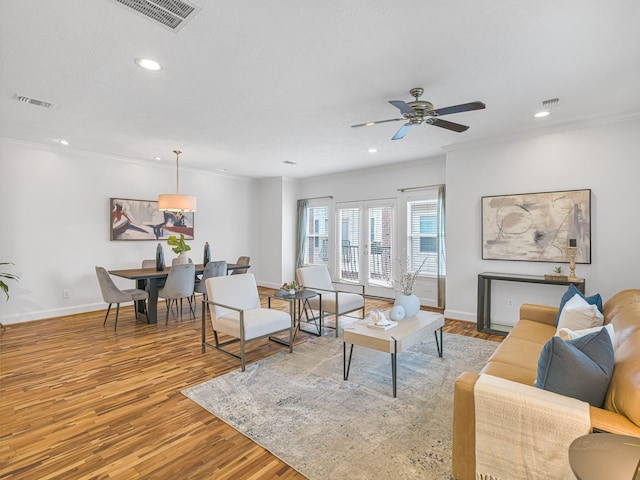 living room featuring light hardwood / wood-style flooring, ceiling fan, and crown molding