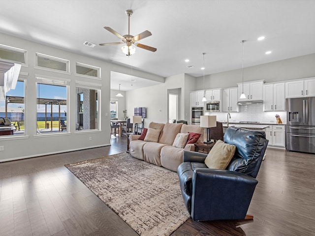 living room featuring ceiling fan, sink, and dark wood-type flooring