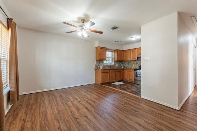 kitchen featuring decorative backsplash, a healthy amount of sunlight, dark wood-type flooring, and appliances with stainless steel finishes