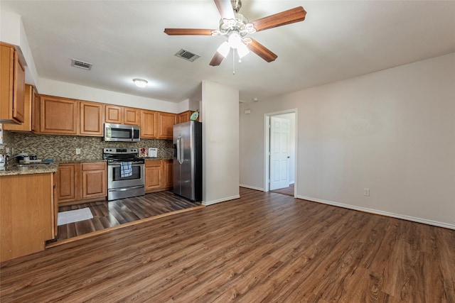 kitchen with light stone countertops, appliances with stainless steel finishes, dark hardwood / wood-style floors, and tasteful backsplash