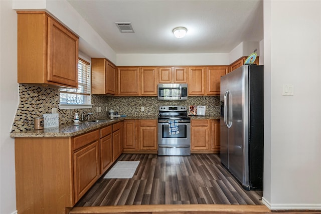 kitchen with tasteful backsplash, dark stone counters, stainless steel appliances, sink, and dark hardwood / wood-style floors