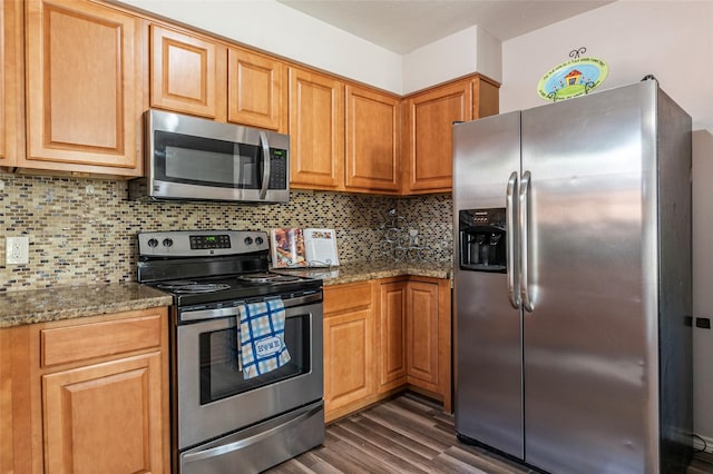 kitchen with stone countertops, decorative backsplash, stainless steel appliances, and dark wood-type flooring