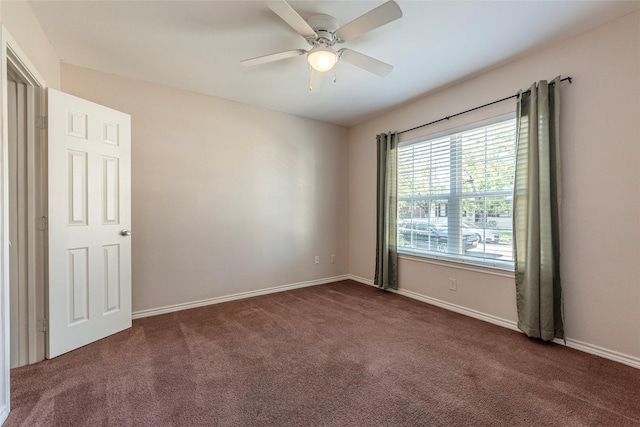 spare room with dark colored carpet and ceiling fan