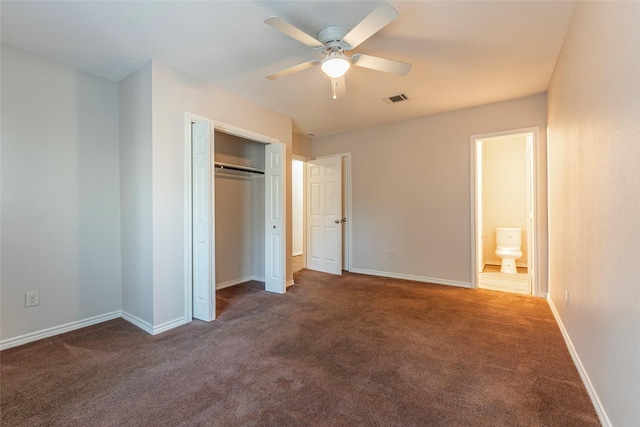 unfurnished bedroom with ceiling fan, dark carpet, and a closet