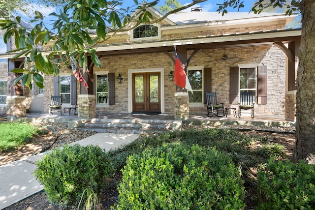 view of front facade featuring stone siding, ceiling fan, a porch, and french doors