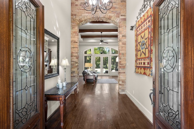 foyer entrance with arched walkways, dark wood-type flooring, baseboards, french doors, and beam ceiling