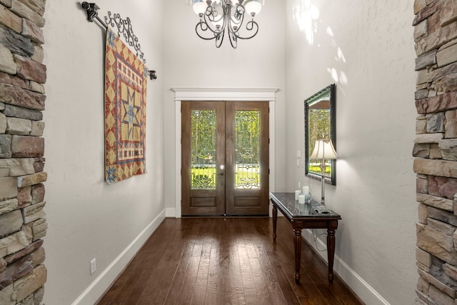 foyer entrance featuring dark wood-style floors, baseboards, an inviting chandelier, and french doors