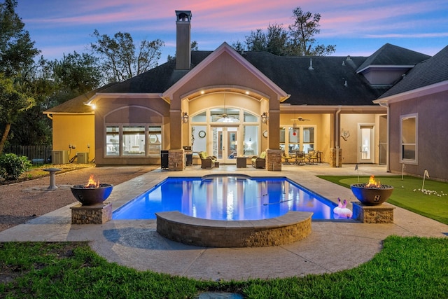 pool at dusk with an outdoor pool, an outdoor fire pit, french doors, and a patio