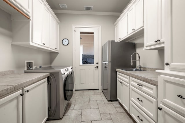 clothes washing area with cabinet space, visible vents, independent washer and dryer, stone tile flooring, and a sink