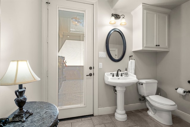 half bathroom with baseboards and toilet