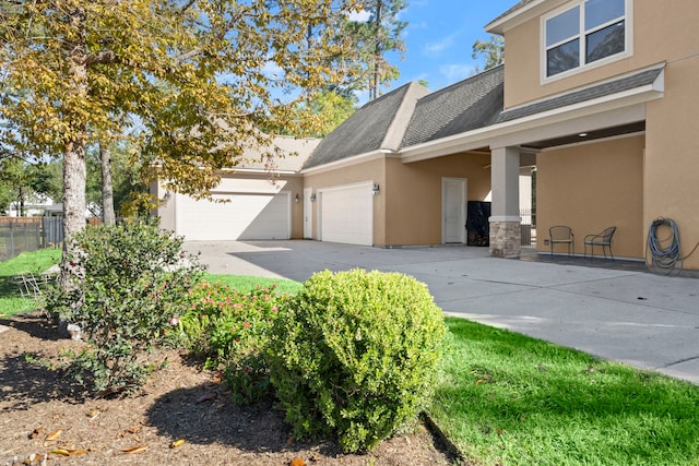 view of front of home featuring an attached garage, fence, concrete driveway, roof with shingles, and stucco siding