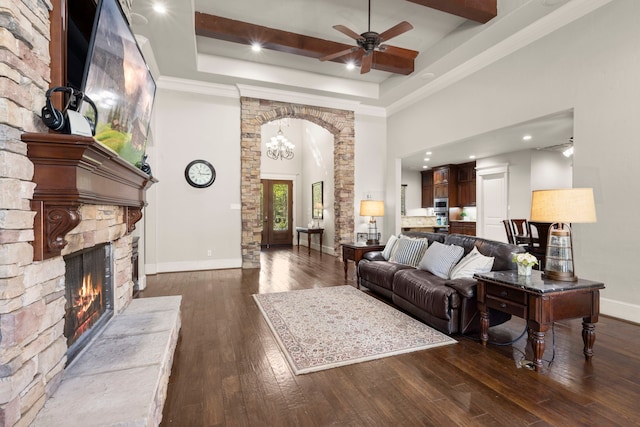 living area featuring baseboards, hardwood / wood-style flooring, ceiling fan, a tray ceiling, and a fireplace