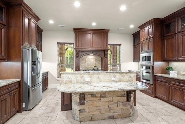 kitchen with stone tile floors, recessed lighting, a wealth of natural light, backsplash, and appliances with stainless steel finishes