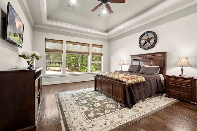 bedroom with dark wood-style floors, ceiling fan, visible vents, and a tray ceiling