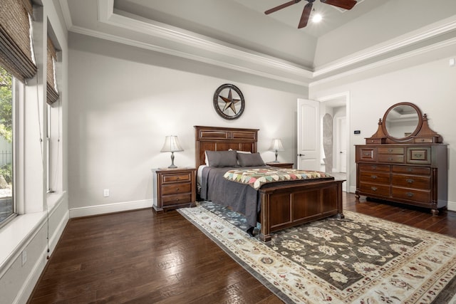 bedroom featuring baseboards, dark wood finished floors, a ceiling fan, a tray ceiling, and crown molding