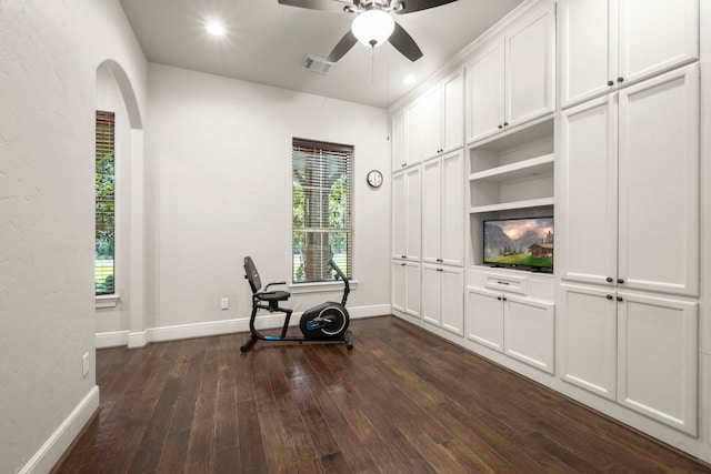 interior space featuring ceiling fan, arched walkways, visible vents, baseboards, and dark wood finished floors