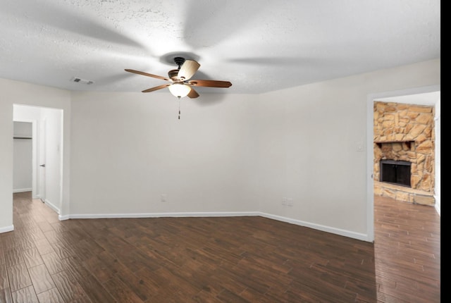 interior space with ceiling fan, dark wood-type flooring, a textured ceiling, and a fireplace