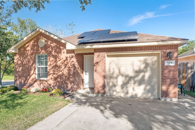 view of front facade featuring a garage, a front yard, and solar panels