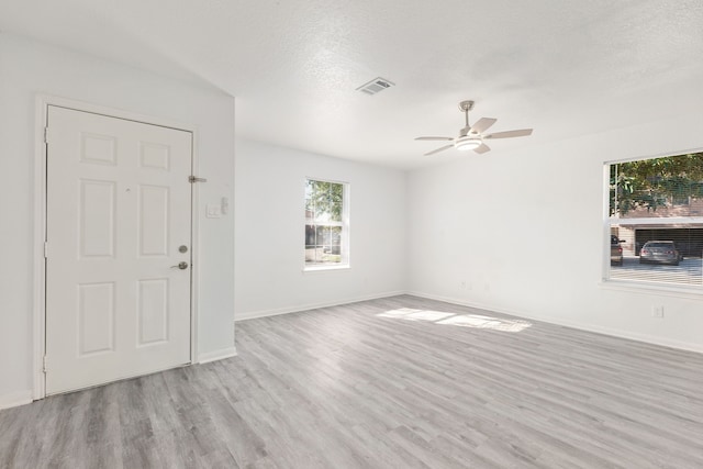 unfurnished living room featuring a textured ceiling, light wood-type flooring, and ceiling fan