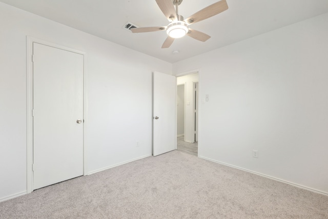 unfurnished bedroom featuring ceiling fan, light carpet, and a closet