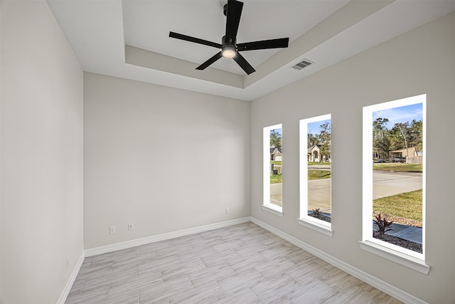 empty room featuring ceiling fan and a raised ceiling