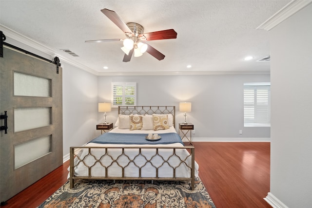 bedroom with dark wood-type flooring, ceiling fan, a barn door, ornamental molding, and a textured ceiling