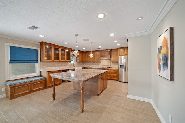 kitchen featuring a breakfast bar, a center island, stainless steel refrigerator with ice dispenser, light wood-type flooring, and decorative light fixtures