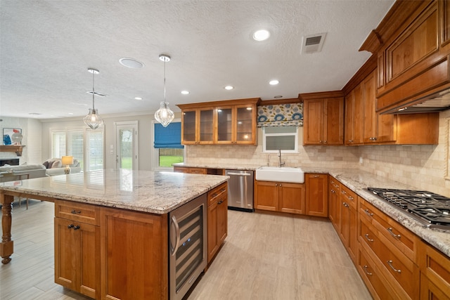 kitchen with hanging light fixtures, sink, wine cooler, light wood-type flooring, and stainless steel appliances