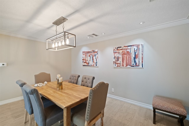 dining room with crown molding, light hardwood / wood-style floors, and a textured ceiling